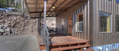 A wooden deck with a metal railing leading to a building entrance.