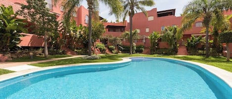 A swimming pool surrounded by palm trees and red buildings.