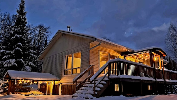 A wooden cabin with a covered deck and stairs leading to the entrance, surrounded by snow. - Peaceful sound's of nature!!right outside the east gate of Algonquin park . (Whitney)