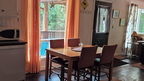 A dining area with a wooden table and chairs, a ceiling fan, and a view of the outdoors. - Peaceful sound's of nature!!right outside the east gate of Algonquin park . (Whitney)
