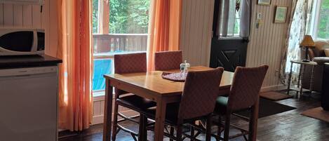 A dining area with a wooden table and chairs, a ceiling fan, and a view of the outdoors.
