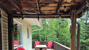 A wooden deck with red and blue Adirondack chairs, a small table, and a dog. - Peaceful sound's of nature!!right outside the east gate of Algonquin park . (Whitney)