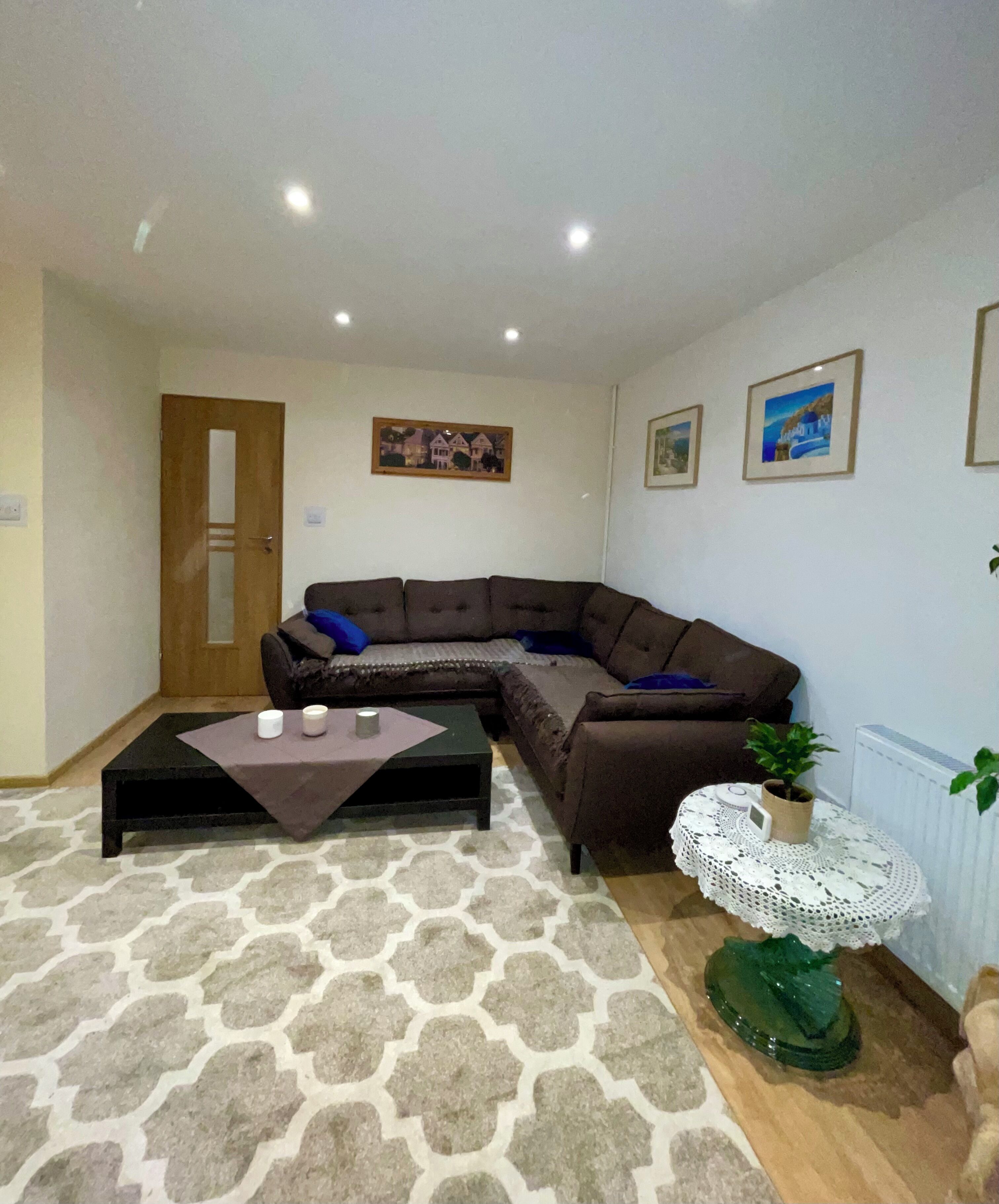 A living room with a sectional sofa, a small coffee table, a patterned rug, and a decorative plant.