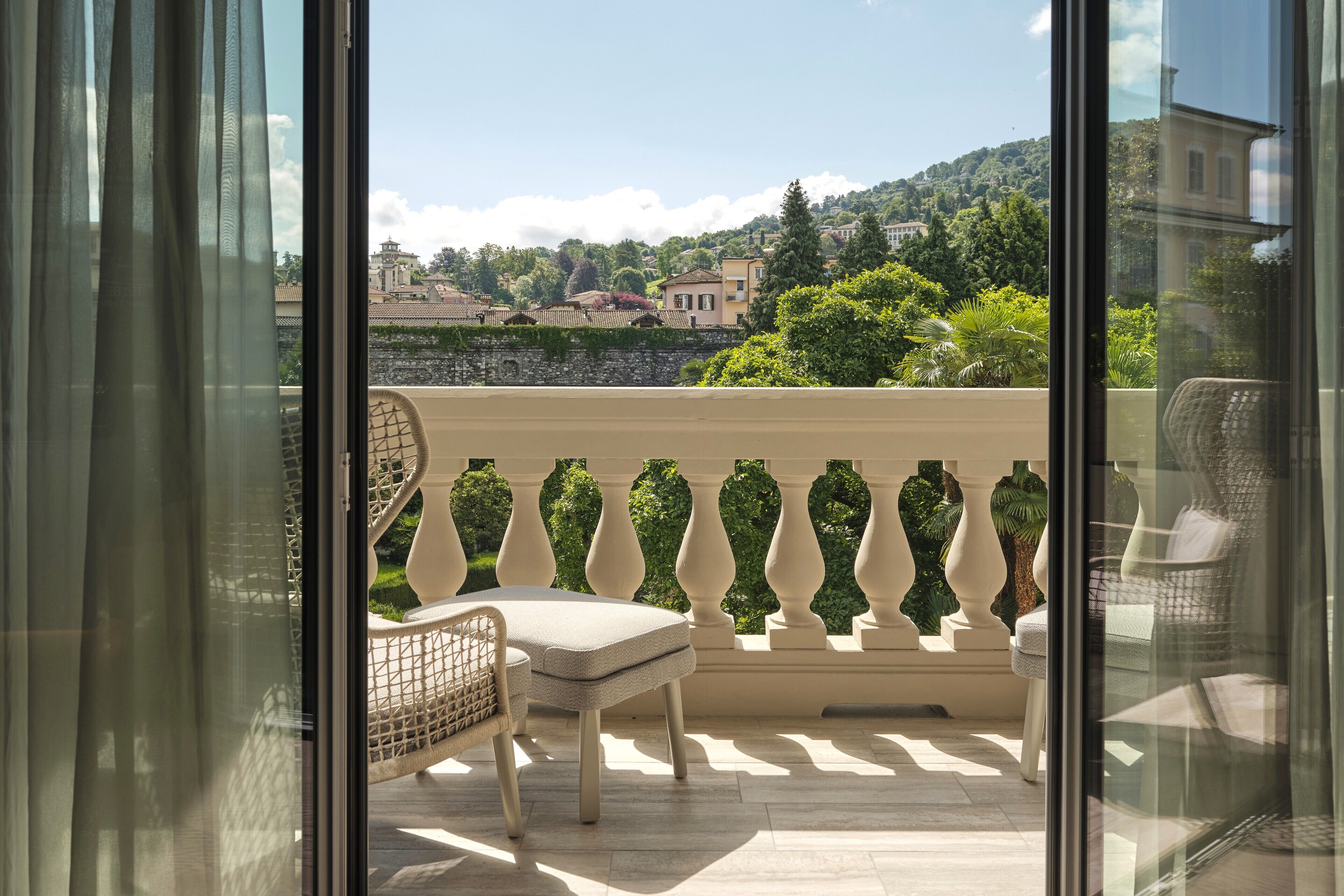 A balcony with a view of a hillside, a chair, and a table.