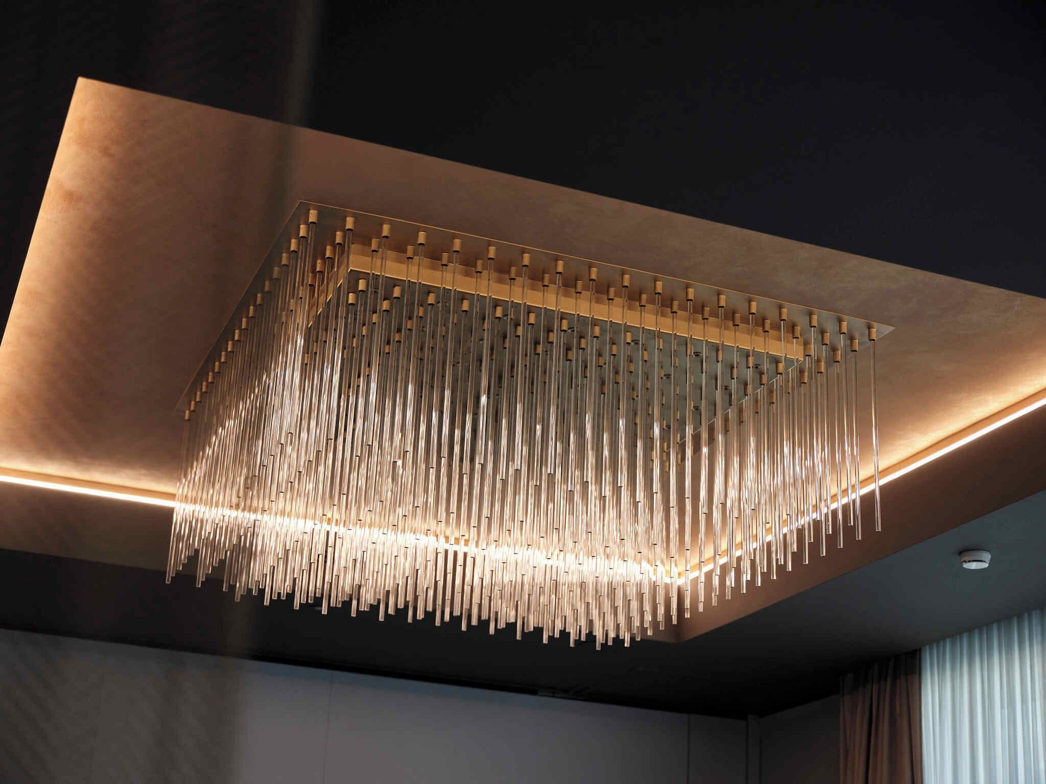 A modern chandelier with multiple hanging elements and integrated lighting.