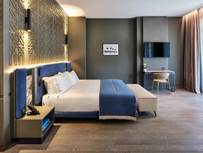Una habitación de hotel moderna con una cama grande, un escritorio con silla, un televisor y un panel decorativo en la pared.