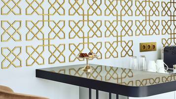 A modern room with a geometric patterned wall, a black table with a gold base, and a brown chair.
