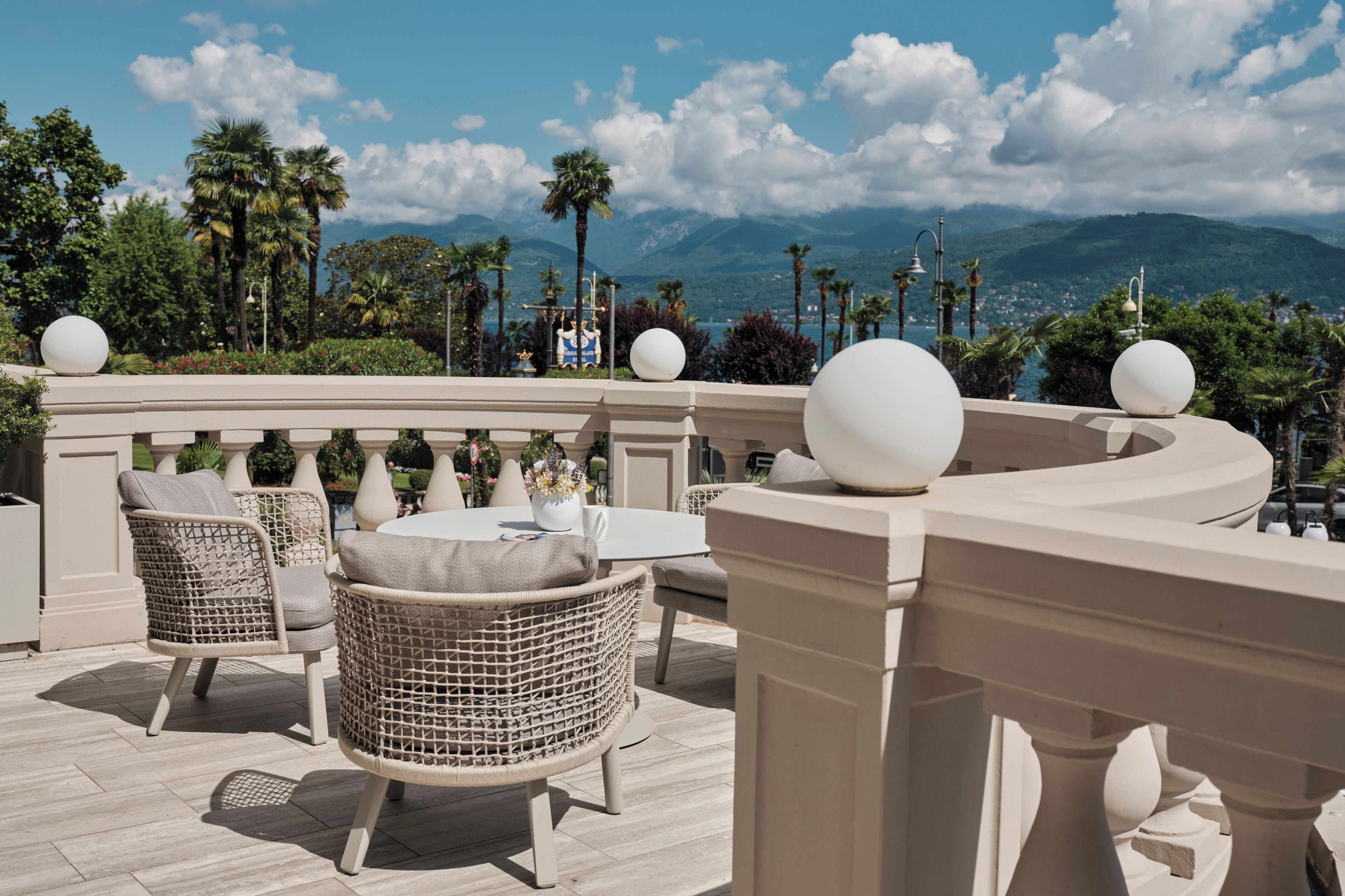 A terrace with wicker furniture, a white table, and decorative spheres.
