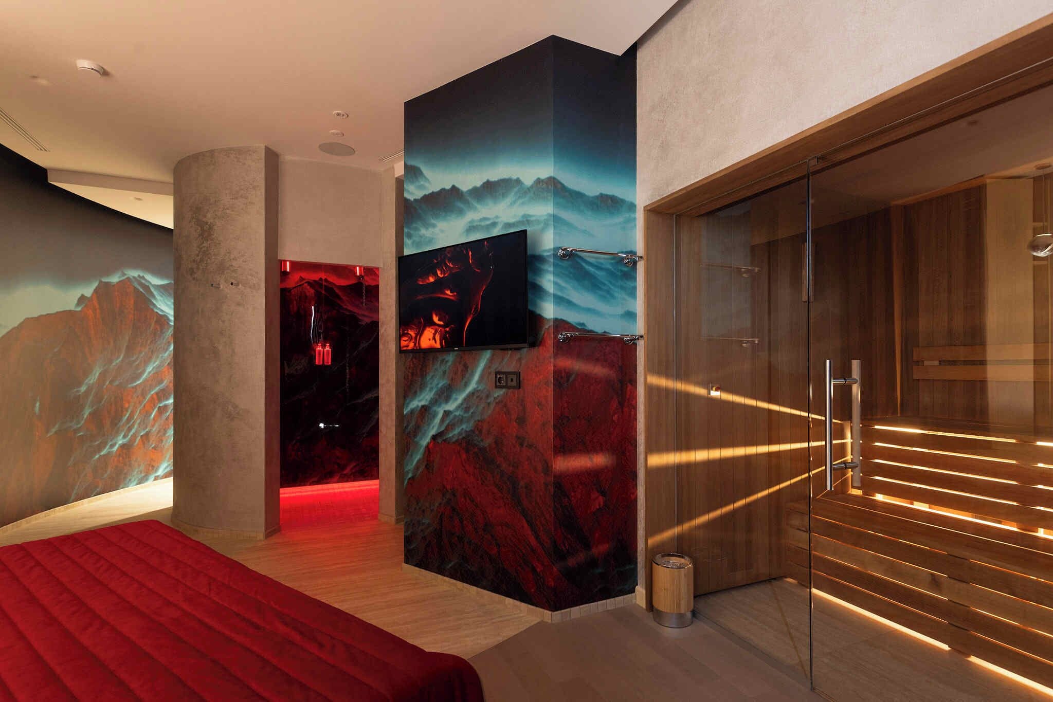 Una habitación de hotel moderna con una cama grande, un televisor montado en la pared y un armario de madera.