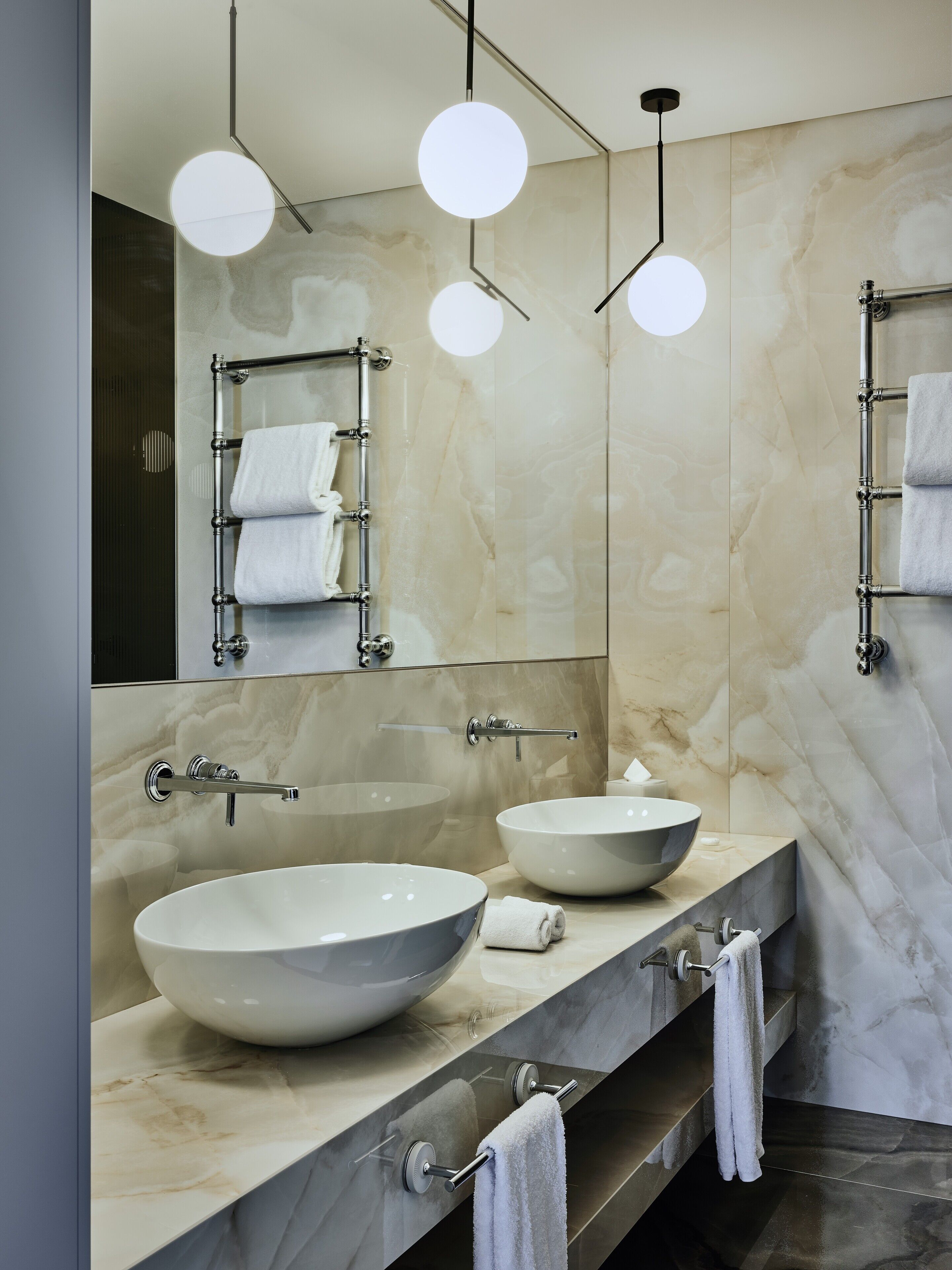 Um banheiro moderno com duas pias grandes sobrepostas, um espelho, porta-toalhas e iluminação pendente.