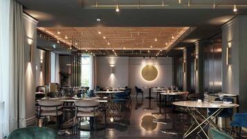 Un restaurant moderne doté de nombreuses tables et chaises, d’un sol en marbre poli et d’un plafond agrémenté de luminaires linéaires.