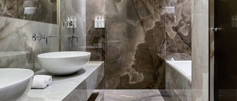 A modern bathroom with a large sink, a bathtub, and a glass-enclosed shower area.