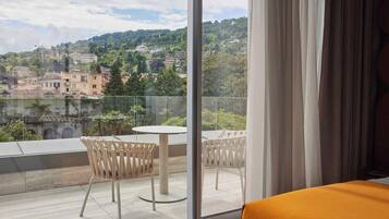 A hotel room with a balcony overlooking a scenic view of a town and hills.