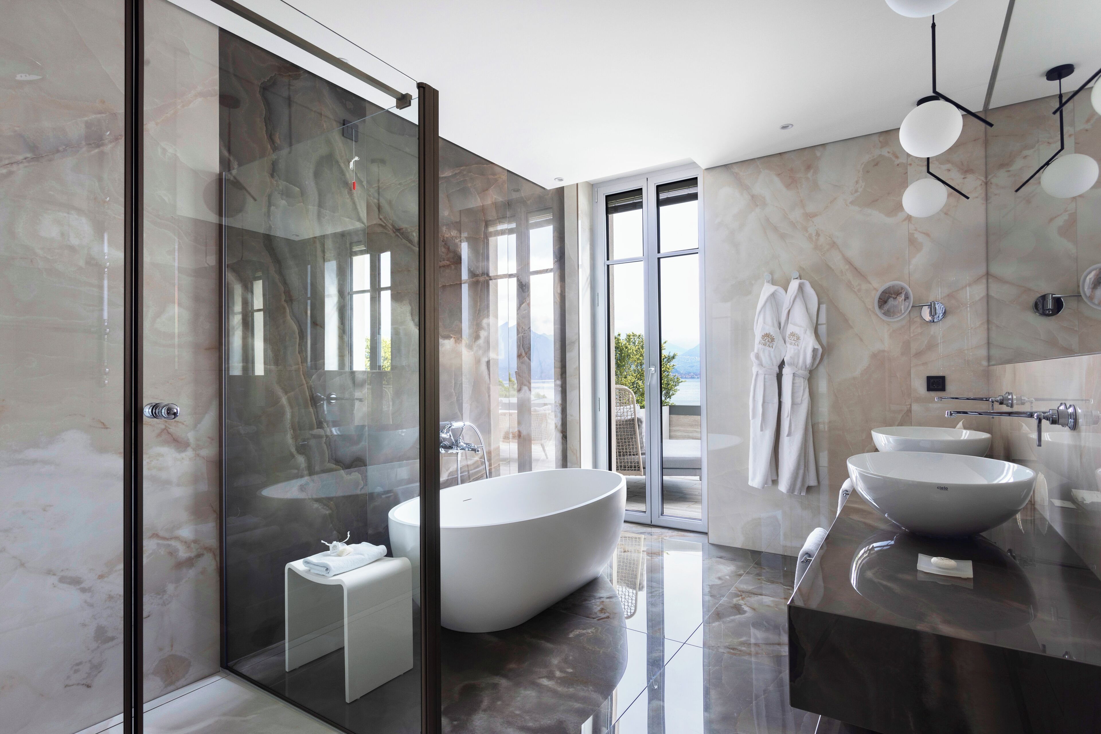 Ein modernes Badezimmer mit einer großzügigen, freistehenden Badewanne, einer gläsernen Dusche und einem Waschtisch mit zwei Becken.