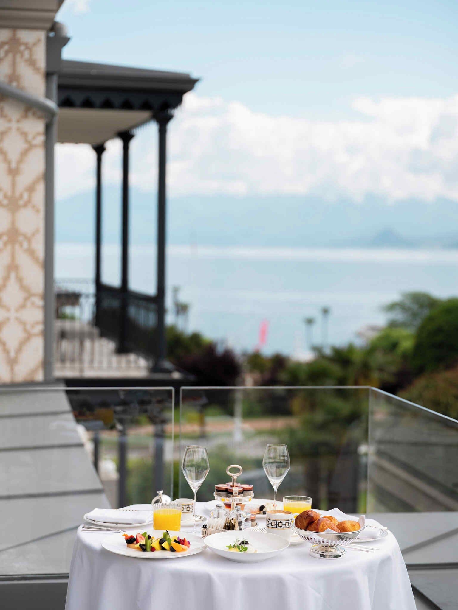 Una mesa dispuesta con alimentos para el desayuno, copas de vino y vista al mar.