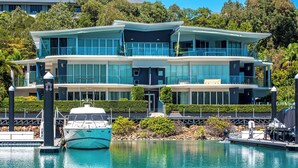 A modern two-story waterfront property with a boat docked in front. - Pavillions 6, Pavilions 6 on Hamilton Island (Hamilton Island)