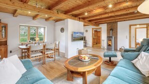 Una sala de estar acogedora con chimenea, muebles de madera y un comedor con vistas al exterior.