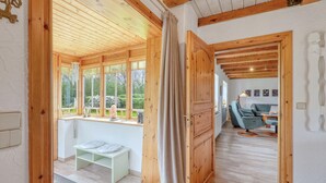 Un interior de madera con un banco, una mesa y vistas al exterior a través de amplios ventanales.