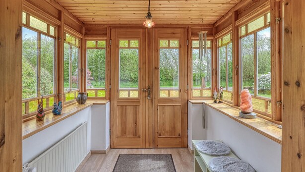 Un interior de madera con ventanas amplias, una puerta central y una lámpara en el techo.