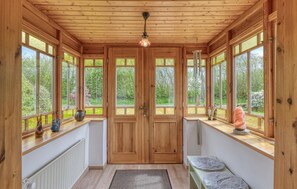A wooden interior with large windows, a central door, and a ceiling light. - 3 bedroom gorgeous home in Tolk (Tolk)