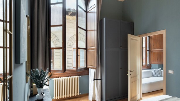 Une chambre avec un grand lit, un radiateur, une armoire et une fenêtre avec des rideaux.