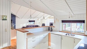 Eine Küche mit weißen Schränken, einer Holz Arbeitsplatte, einem eingebauten Geschirrspüler und einem Fenster mit Blick ins Freie.