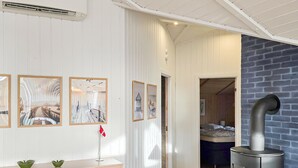 Ein Zimmer mit weißer Wandverkleidung, einem Bett, einem Kamin und Kunstwerken.