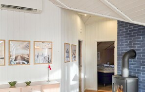 A room with a white paneled wall, a bed, a fireplace, and artwork.