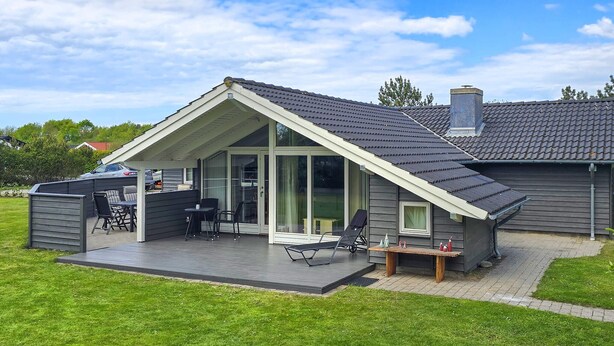 Ein modernes Haus mit überdachter Terrasse, einer Auffahrt und einem großen Schiebeglastür.