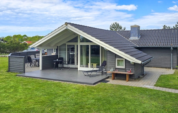 A modern house with a covered patio, a carport, and a large sliding glass door.