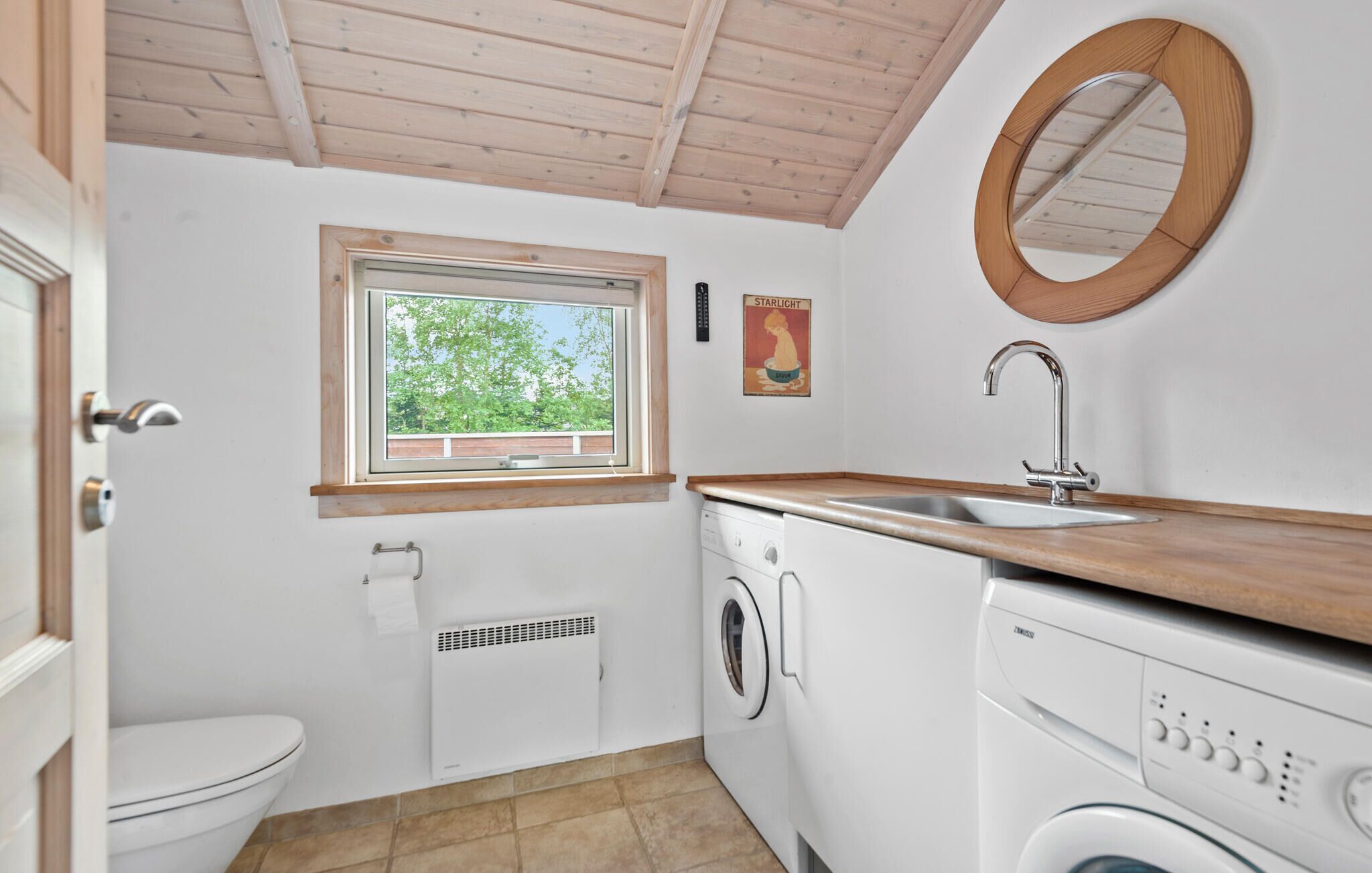 Une petite cuisine équipée d’un évier, d’une fenêtre, d’un lave-linge et de toilettes.