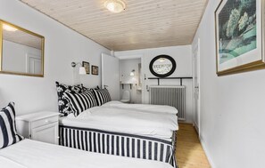 Makuuhuoneessa on sänky, yöpöydät, peili, patteri ja seinällä oleva kehystetty taulu.