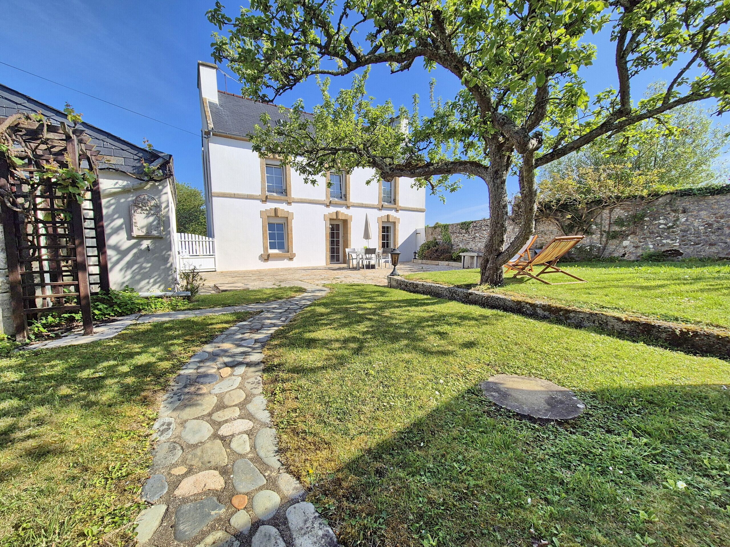 A two-story white building with a stone pathway leading to a patio area.