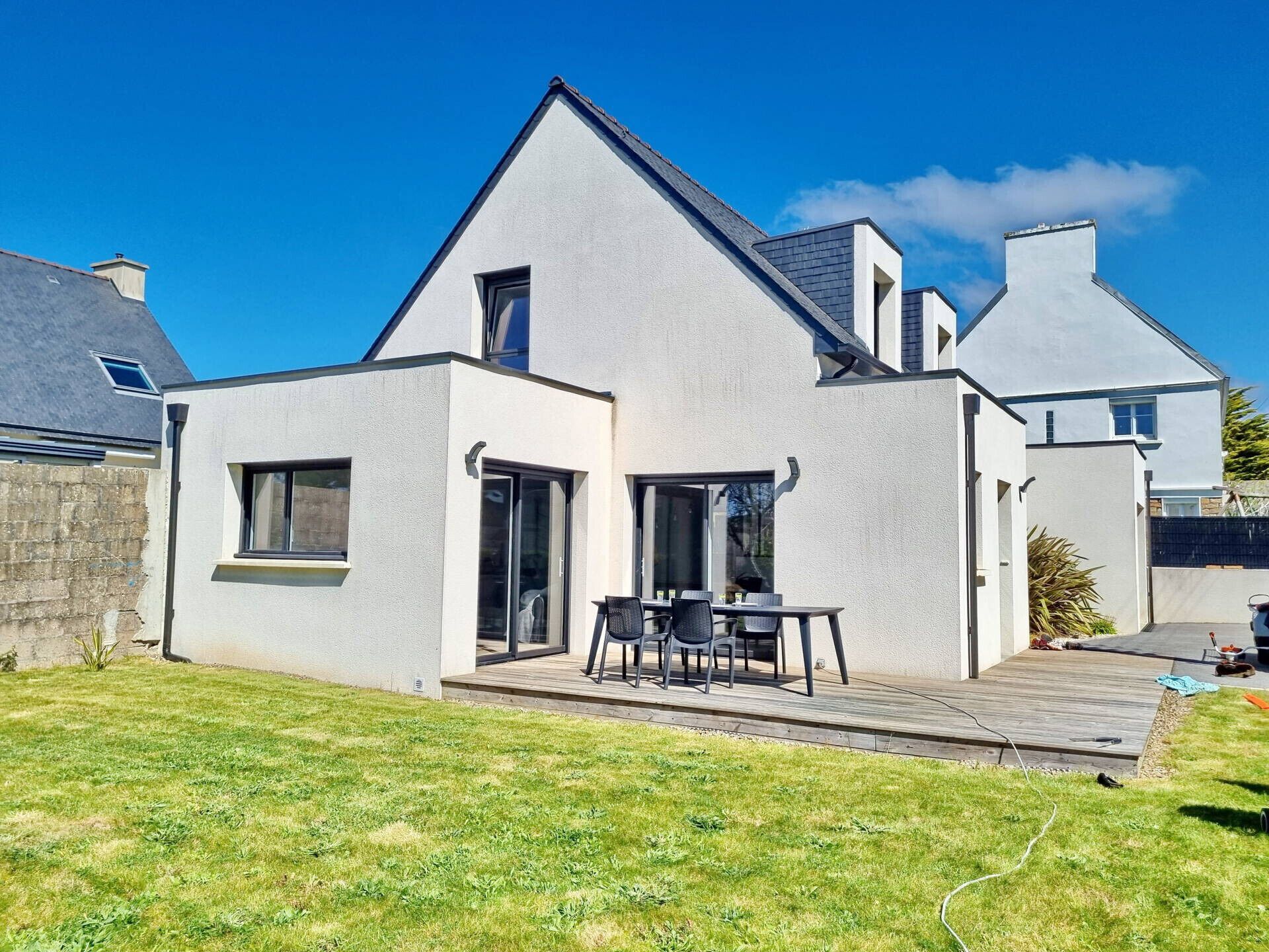 Ein modernes, zweistöckiges Haus mit Terrasse, großen Fenstern und einer sichtbaren Garage.