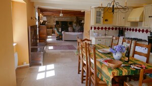 Un coin repas avec une table dressée pour deux personnes, des chaises en bois, un vase rempli de fleurs et un lustre.