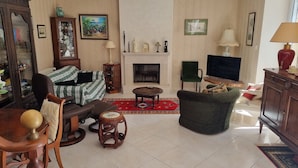 A living room with a fireplace, a television, and a green armchair.