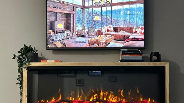 A television displaying a cozy living room with a fireplace below. - Higgi Drive 5 - Mt Hotham (Hotham Heights)