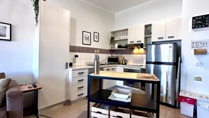 A modern kitchen with white cabinets, stainless steel appliances, and a small dining area with a table and chairs. - Higgi Drive 5 - Mt Hotham (Hotham Heights)
