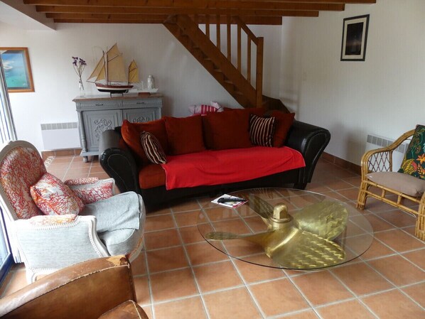 Una sala de estar con un sofá rojo, una mesa de centro de vidrio y una escalera de madera.