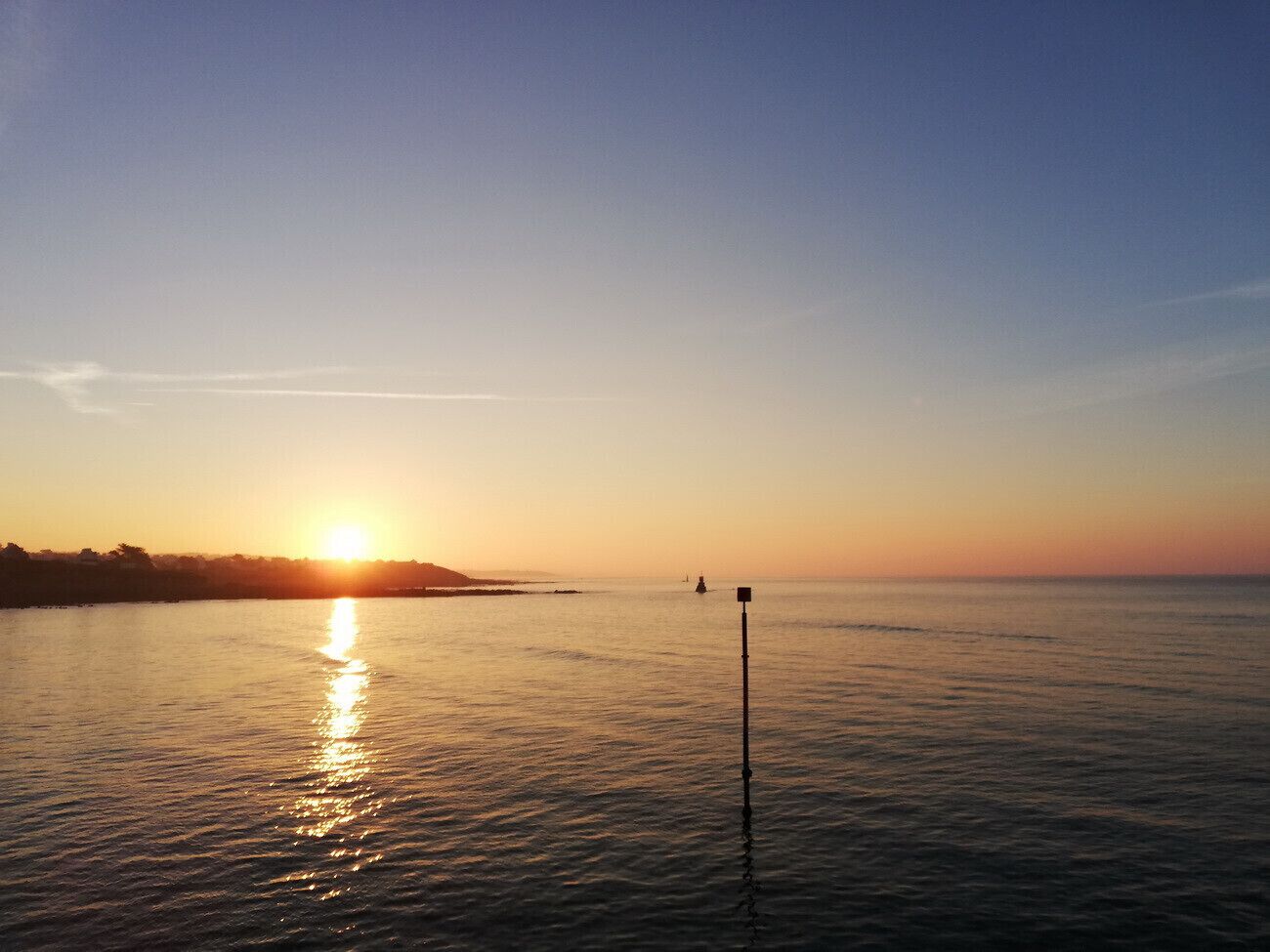 A calm body of water with a clear horizon and a distant landmass.