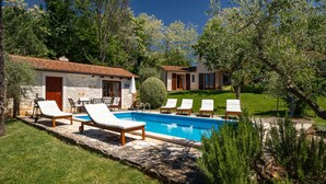 A pool with lounge chairs, a stone building, and a well-maintained lawn.