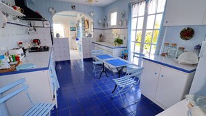 Una cocina con azulejos azules, armarios blancos y un comedor con sillas azules.