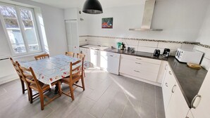 A kitchen with white cabinets, a dining table with a map tablecloth, and a window with blinds.