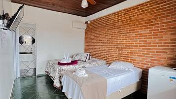 Una camera da letto con due letti, una parete in mattoni, una ventola a soffitto e un frigorifero.