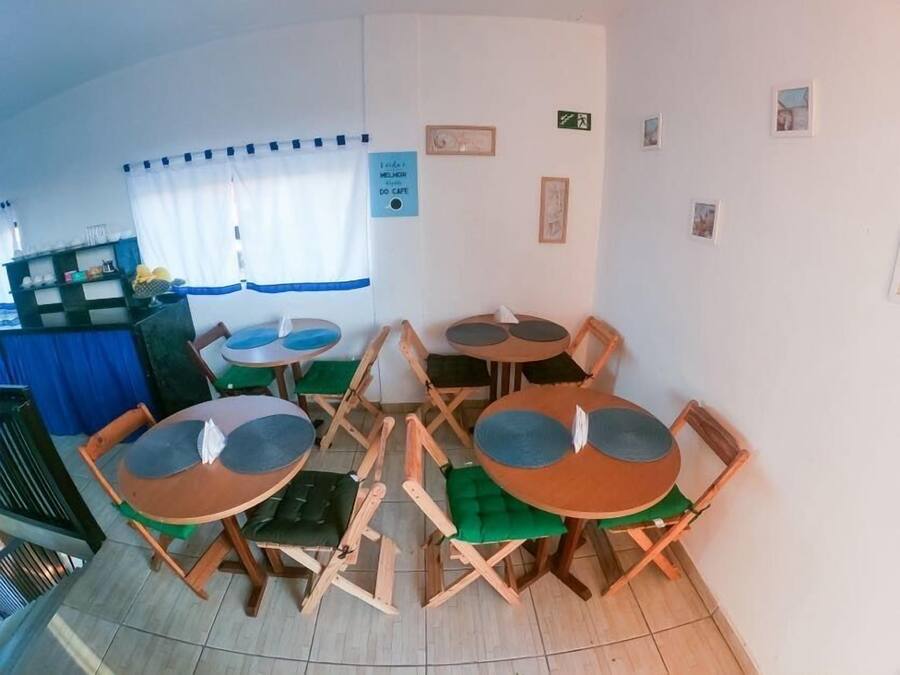 Una zona de menjador amb diverses taules i cadires rodones, una cortina blava i un senyal que indica una cafeteria.
