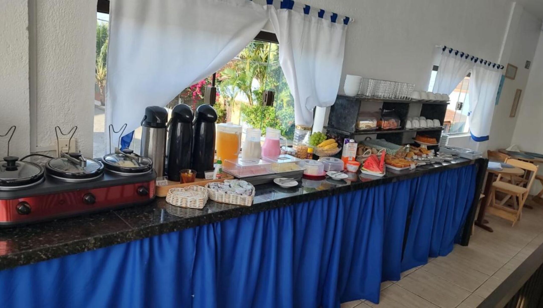 Ein reichhaltiges Buffet mit verschiedenen Speisen und Getränken, darunter Früchte, Säfte und heiße Getränke.