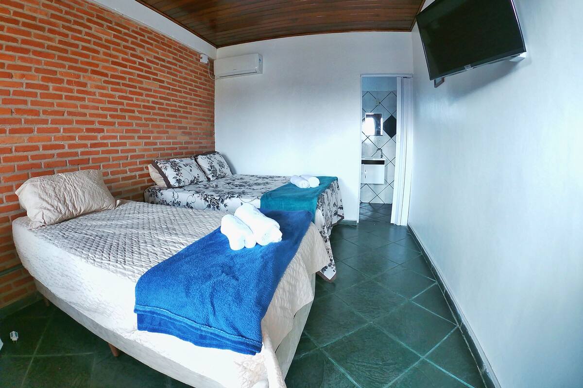 Una habitación con dos camas, un televisor montado en la pared y un equipo de aire acondicionado.
