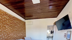 Habitación de hotel con pared de ladrillo, cama con ropa de cama blanca, manta azul y almohada con forma de cisne.