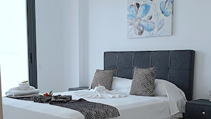 A modern bedroom with a large bed, a nightstand, and a wall-mounted artwork. - Larvella Estia Luxury Suites (Larnaca)
