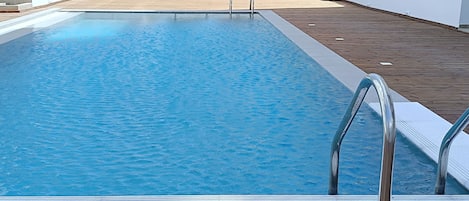 A rectangular swimming pool with a wooden deck surrounding it.